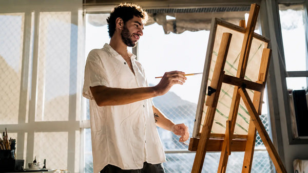 Artiste peignant sur un chevalet en bois dans un atelier lumineux, image d’inspiration pour chevalet de peinture.